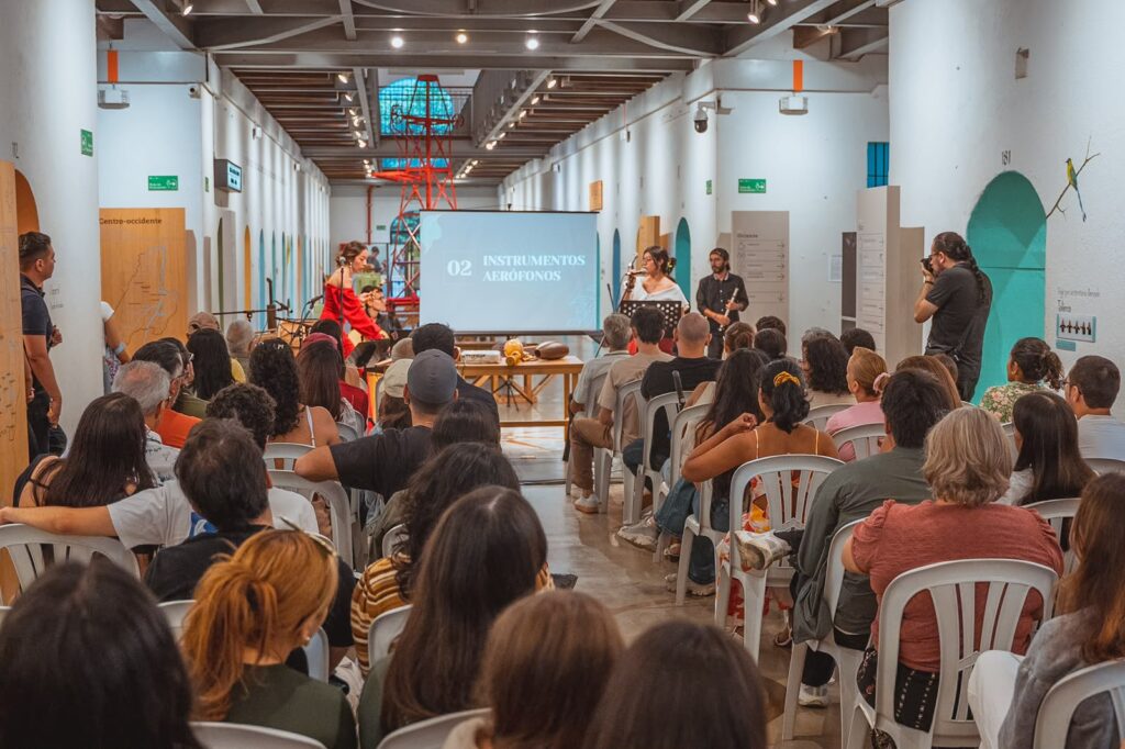 Público sentado en un salón durante una presentación sobre instrumentos musicales en Ibagué.